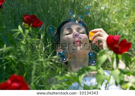 teen girl in the grass blowing soap balloons