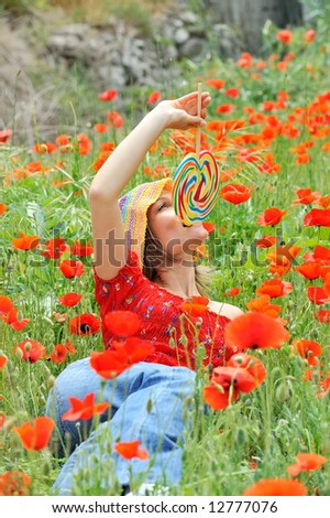 funny girl with colorful lollipop on a field with poppies