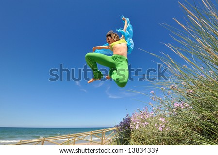 girl with blue silk scarf jumping on the beach