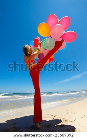 young woman with colorful balloons jumping on the beach