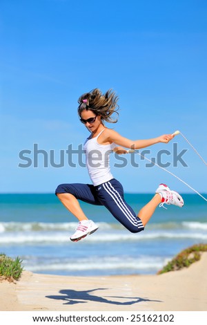 young woman with jumping rope on the beach