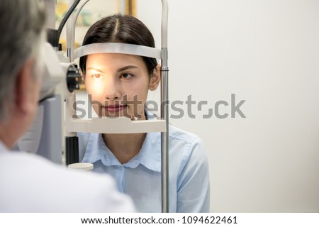 Opitcian with patient. Senior chinese optician with his asian woman patient in Optician room examine her eye. Real optician room in hospital. Medical concept.