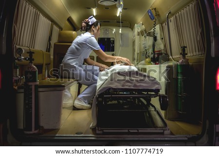 Nurse with patient. Young chinese nurse with her emergency patient in ambulence taking care of her patient. Real ambulence in hospital. Medical concept.