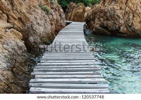 Old vintage wooden walking bridge over sea water, taken on a sunny day