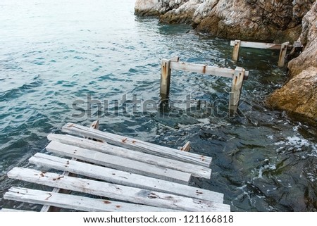 Old vintage wooden walking bridge over sea water, taken on a sunny day