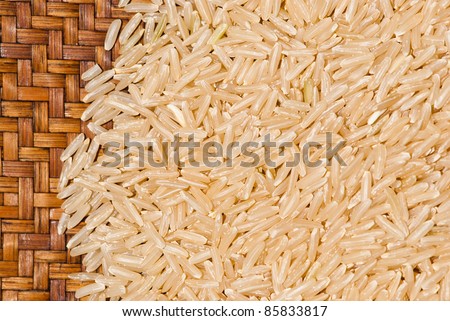 Close up shot of brown rice on a brown bamboo plate displaying a symbol of vitality and world food/hunger. Can be use for various concepts relate to food, hunger, poor people, world food, and wealth.