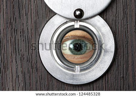 Peephole with eye close-up on a wooden door horizontally
