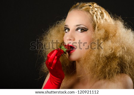 Blonde woman with creative hairstyle eating a strawberry