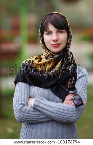 Portrait of young woman in park with a scarf on a head