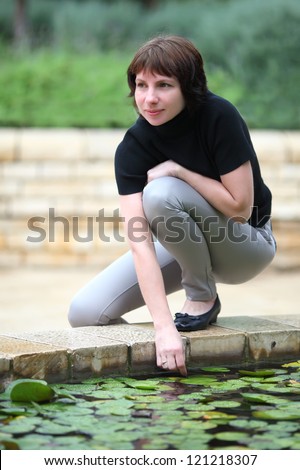young woman near the fountain,put her hand into the water