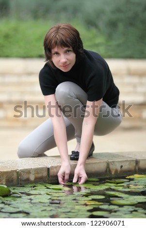 young woman near the fountain,put her hand into the water