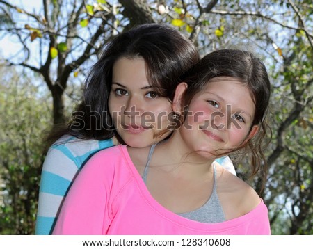 Two sisters hug one another outdoors