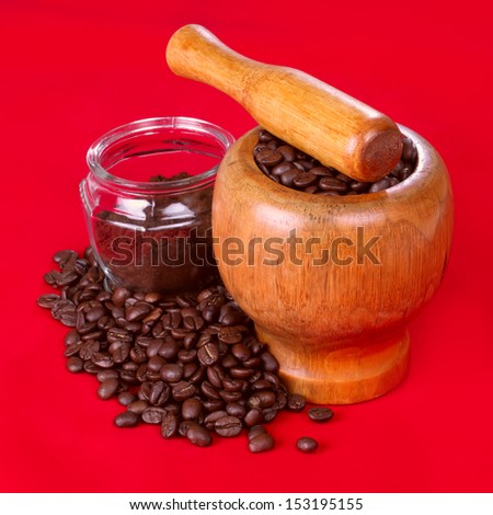 Mortar and pestle with black coffee and coffee beans on red background