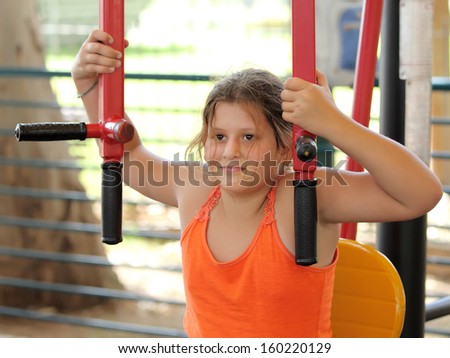 A little girl on a gym machine in the public fitness park