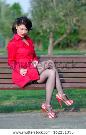 Beautiful young women in red coat posing in park