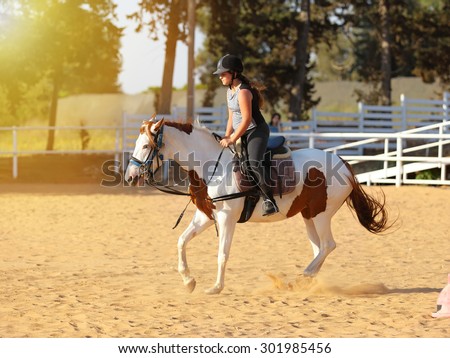 Horseback riding, lovely equestrian - young girl is riding a horse