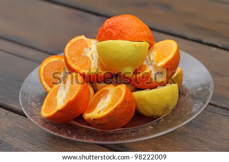 A fruit plate of oranges and lemons on a wet wooden table after rain