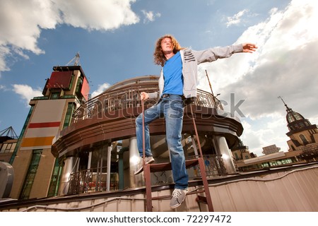 Young happy man with long hair, sky and metal structure on background