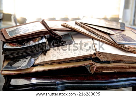 Old books, albums and photos on antique table.