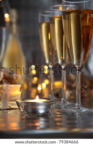 Champagne in glasses,gift boxes,candle light and twinkle lights on background.