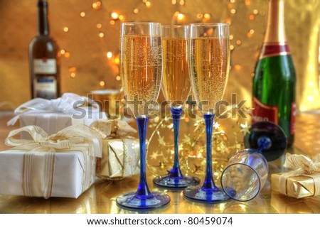Champagne in glasses ,gift boxes and lights on gold background.