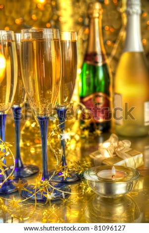 Champagne in glasses ,bottles,candle,gift on gold background.