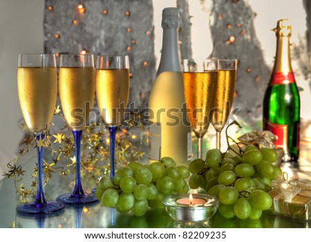 Champagne in glasses,bottles,grapes and twinkle lights on background.