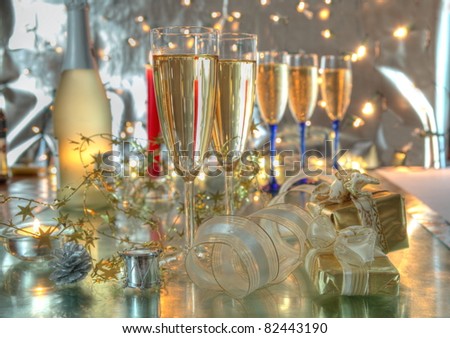 Champagne in glasses,bottle, gift boxes, candles and twinkle lights on background.
