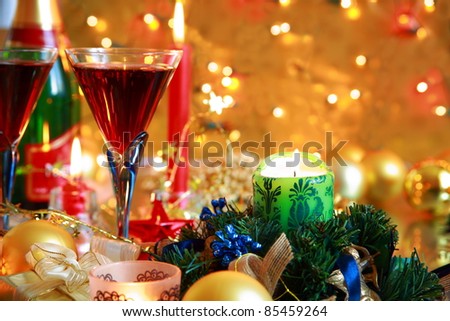 Red wine in glasses and candle lights on golden background with twinkle lights.