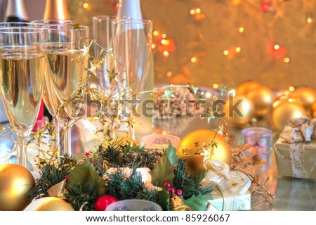 Champagne in glasses,bottles,candle lights,baubles,green twig on background with twinkle lights.