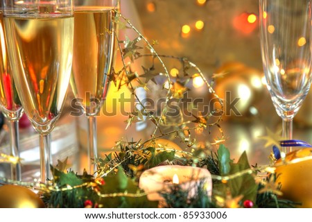 Closeup of champagne in glasses,baubles,candle lights on golden background with twinkle lights.