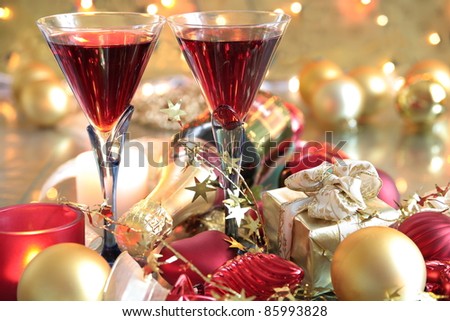Red wine in glasses,baubles,candle lights on golden background with twinkle lights.