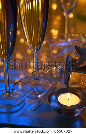 Closeup of champagne in glasses,candle lights,gift and twinkle lights on background.