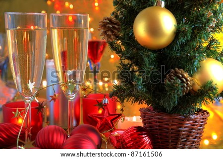 Champagne in glasses and christmas tree,baubles and candle lights on golden background with twinkle lights.