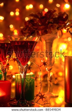 Red wine in glasses, candle lights, flowers and twinkle lights on background.
