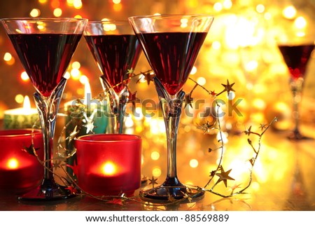 Red wine in glasses,candle lights and twinkle lights on golden background.