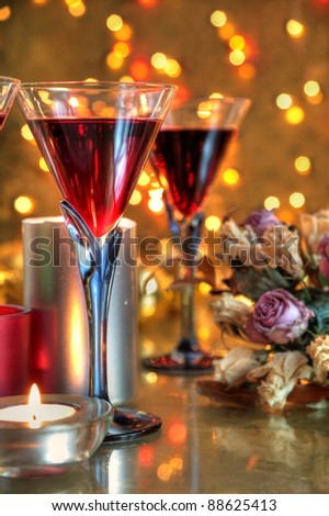 Closeup of red wine in glasses,candle lights and blurred flowers on background with twinkle lights.