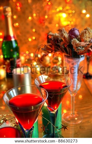 Closeup of red wine in glasses ,candle lights and flowers on gold background with twinkle lights.