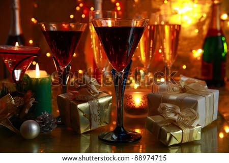 Red wine in glasses,candle lights,gift boxes,bottles and blurred background with twinkle lights and glass of champagne.