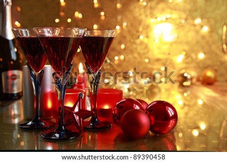Red wine in glasses,bottle,candle lights,baubles on golden background with twinkle lights.