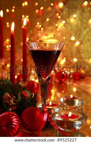 Red wine in glasses,baubles,candle lights on golden background with twinkle lights.