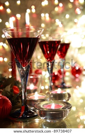 Closeup of red wine in glasses,candle lights and baubles on background with twinkle lights.