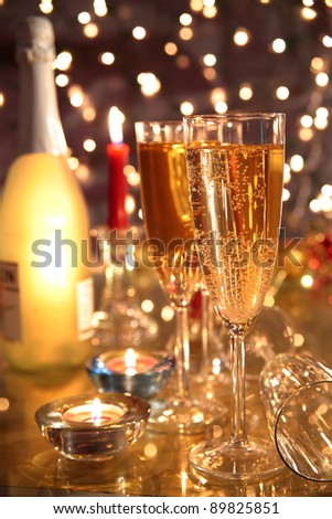 Champagne in glasses,bottle,candle lights on background with twinkle lights.