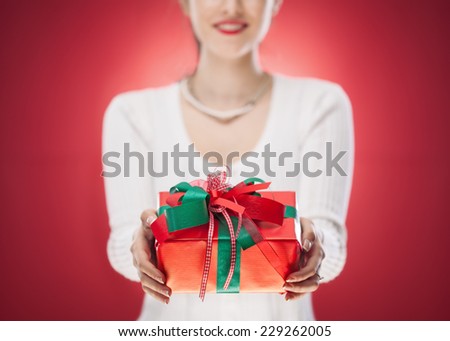Woman holding a gift box in a gesture of giving.