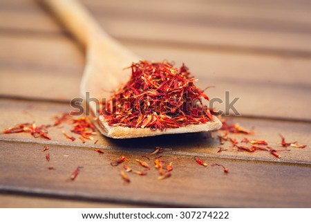 Spoonful of dry red saffron threads on wooden background