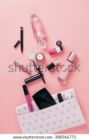 Make up bag with cosmetics on pink background