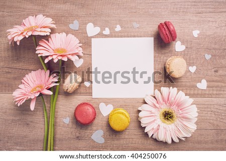 Mothers Day message with pink flowers and multi colored macarons on wooden table