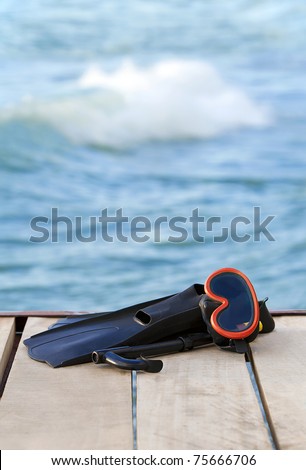 A view of diving goggles, swimming fins and snorkel near the lake