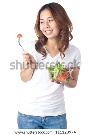 Young healthy woman holding vegetable salad in plastic bowl and looking to the pieces of tomato on fork on white background