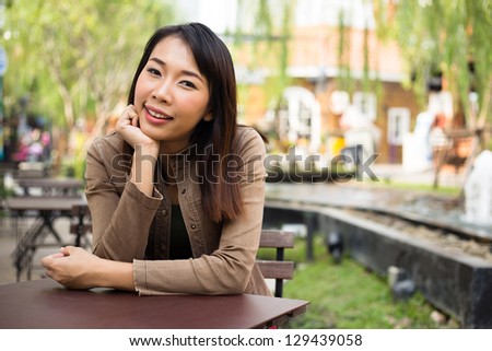 Young asian woman sitting at sidewalk cafe